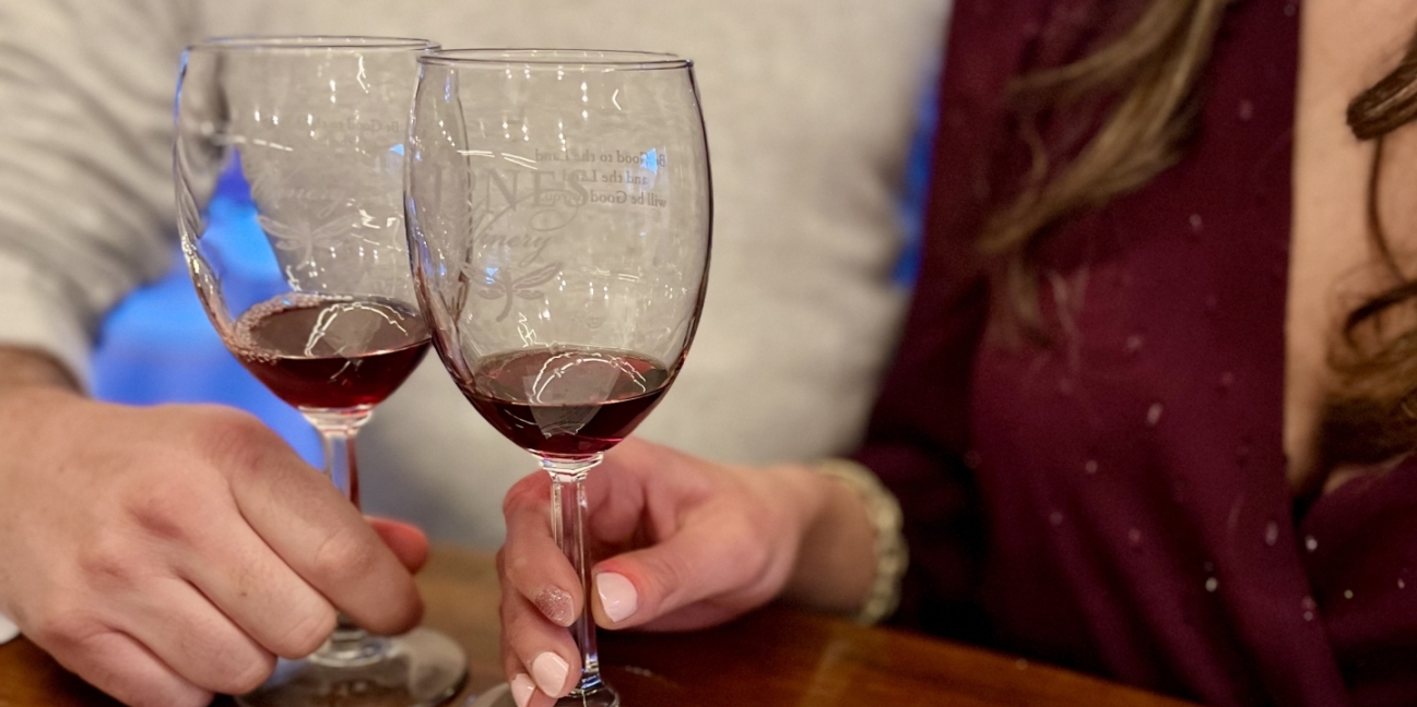 Two people with two wine glasses at a wood topped bar